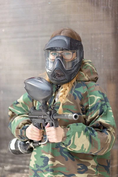 Girl playing paintball in overalls with a gun. — Stock Photo, Image