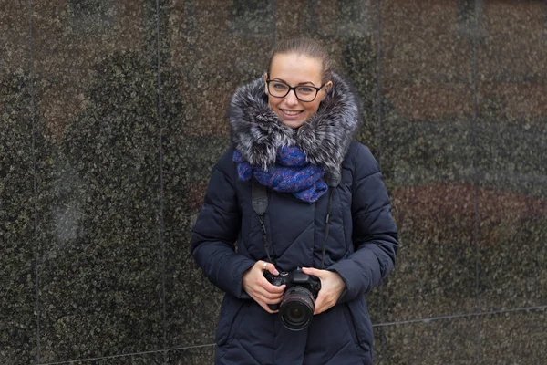 Belle fille avec un appareil photo sur un fond de marbre mur sombre — Photo