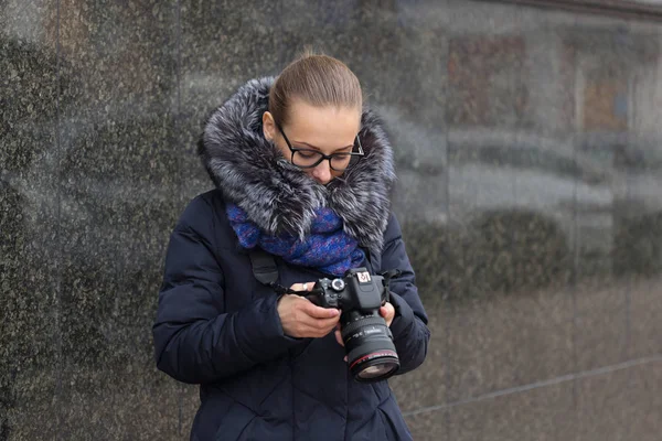 Schöne Mädchen mit einer Kamera auf dem Hintergrund einer dunklen Wand aus Marmor — Stockfoto