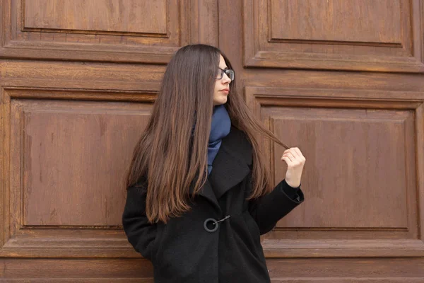Portret van een mooi meisje op de achtergrond van een grote houten deur — Stockfoto