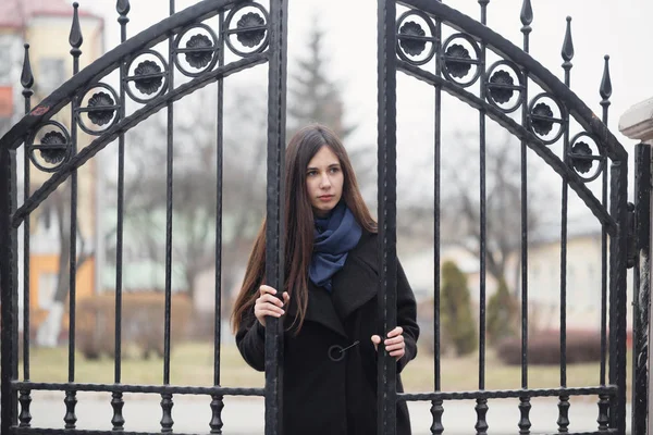 Retrato de una hermosa chica cerca de la puerta de hierro forjado — Foto de Stock
