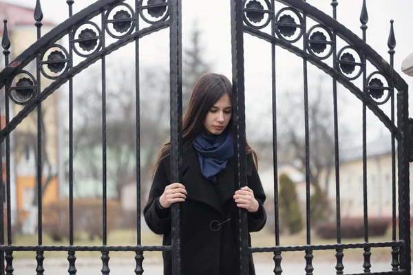 Retrato de una hermosa chica cerca de la puerta de hierro forjado — Foto de Stock