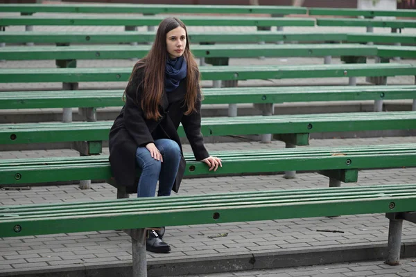 Retrato de una hermosa chica en un banco verde — Foto de Stock