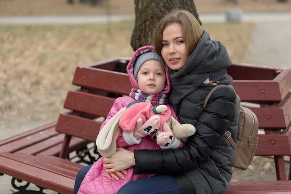 Mãe e filha estão sentados em um banco de parque — Fotografia de Stock