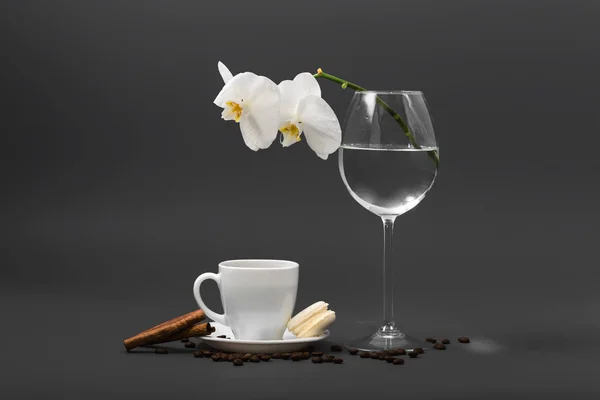 Λευκή ορχιδέα σε ένα ποτήρι και ένα φλιτζάνι καφέ — Φωτογραφία Αρχείου