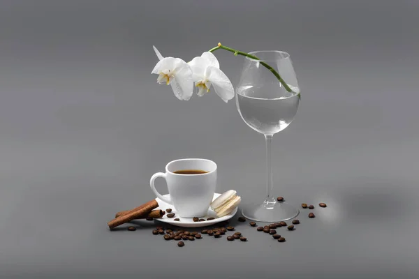 Weiße Orchidee in einem Glas und einer Tasse Kaffee — Stockfoto