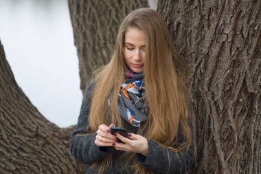 Güzel bir kız ile bir telefon açık havada erken baharda portresi.