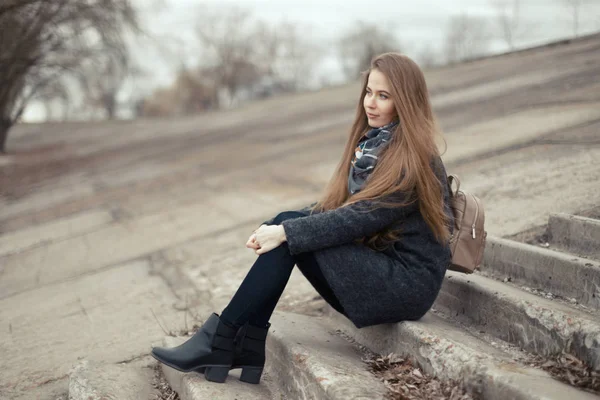 Retrato de una hermosa niña a principios de primavera en los escalones — Foto de Stock