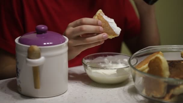 Un adolescente come panqueques con crema agria — Vídeo de stock