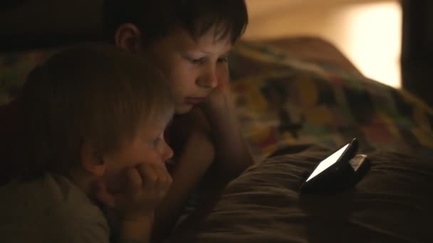 Kinderen kijken naar tekenfilms in een donkere kamer — Stockvideo