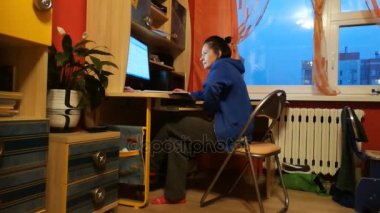 Evde bir bilgisayar üzerinde çalışan kadın