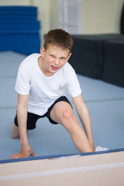 O jovem realiza exercícios de ginástica no ginásio. . — Fotografia de Stock