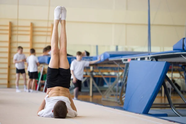 El joven realiza ejercicios de gimnasia en el gimnasio. . — Foto de Stock