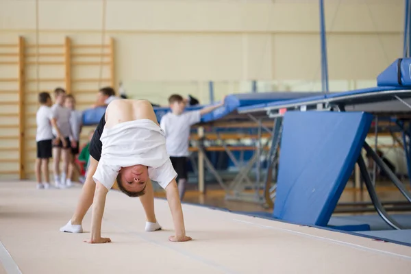 O jovem realiza exercícios de ginástica no ginásio. . — Fotografia de Stock