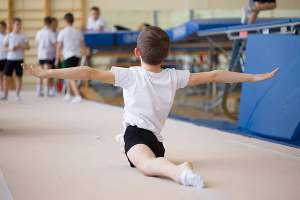 O jovem realiza exercícios de ginástica no ginásio. . — Fotografia de Stock