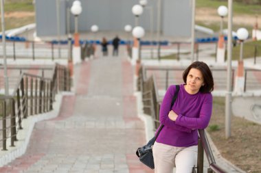 Bir kadın bir mor kazaklı merdivenlerde duruyor