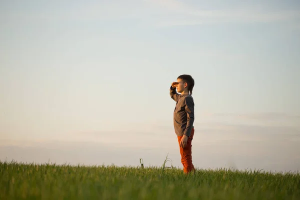 Nastolatek jest stojący w wysokiej trawie o zachodzie słońca — Zdjęcie stockowe