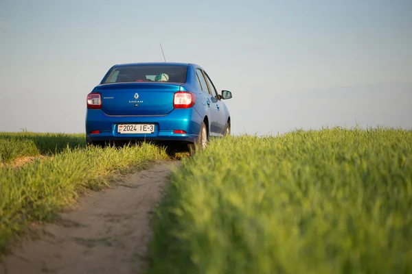 Homel, Wit-Rusland - 6 mei 2017: blauwe auto Renault Logan geparkeerd in een veld op een landweg. — Stockfoto