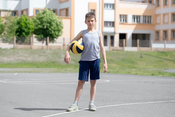 Підліток у футболці та шортах грає з м'ячем — стокове фото