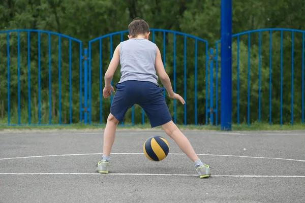 Teenager in T-Shirt und kurzer Hose, der mit einem Ball spielt — Stockfoto