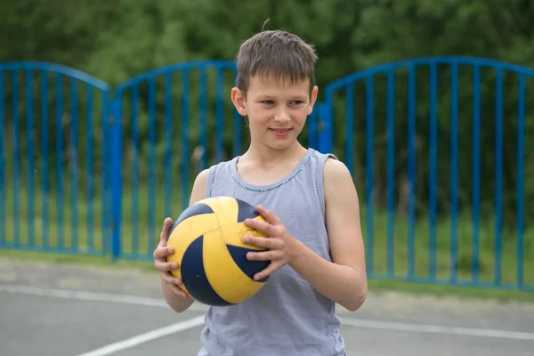 Ein Teenager in Weste hält einen Ball in der Hand — Stockfoto