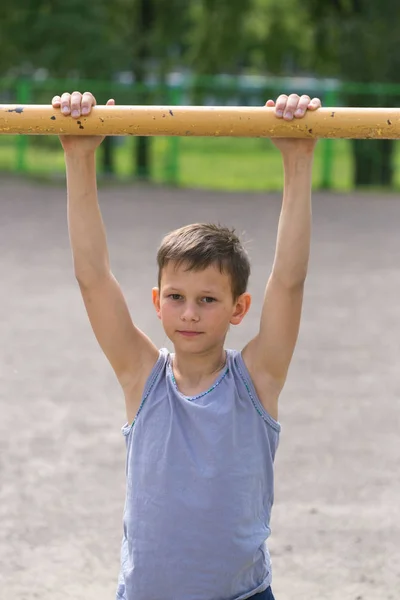Подросток в футболке занимается гимнастикой на горизонтальной полосе — стоковое фото