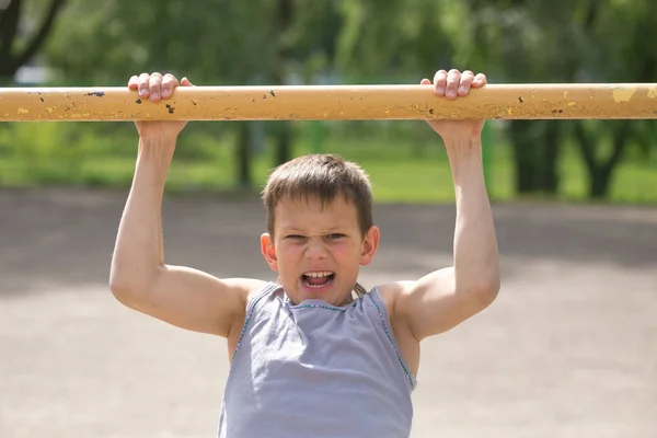 Um adolescente em uma camiseta está envolvido em ginástica em uma barra horizontal — Fotografia de Stock