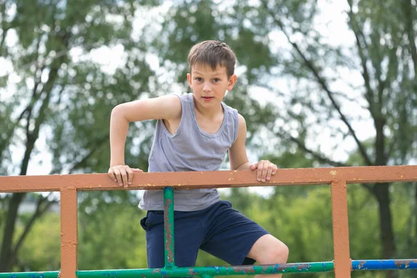 Un adolescente in maglietta è impegnato in ginnastica su una barra orizzontale — Foto Stock
