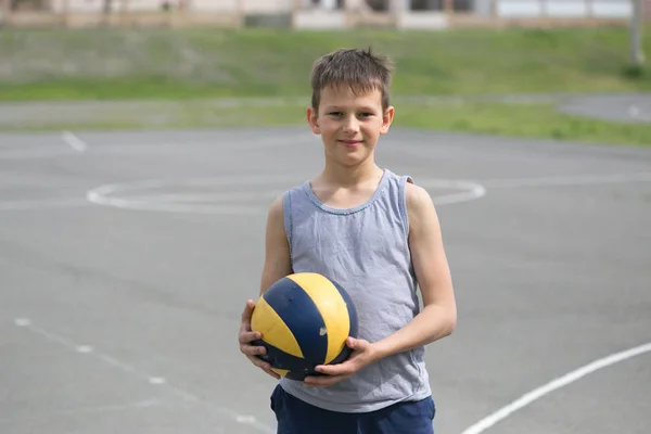 Um adolescente de colete segura uma bola na mão — Fotografia de Stock