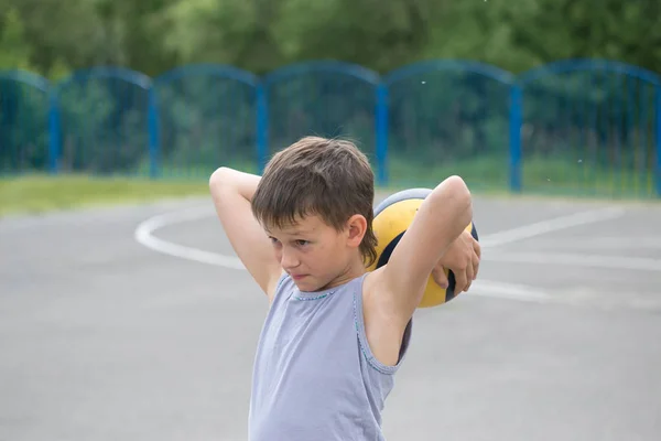 Um adolescente de colete segura uma bola na mão — Fotografia de Stock