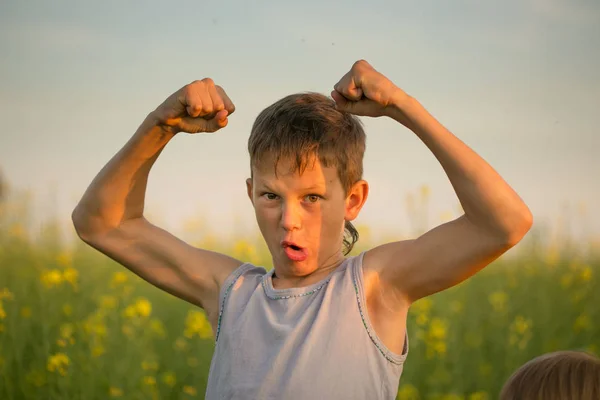 Ragazzo su un campo di colza giallo la sera al tramonto — Foto Stock