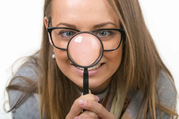 Vacker flicka på en vit bakgrund med förstoringsglas — Stockfoto