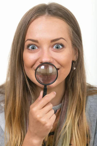 Vacker flicka på en vit bakgrund med förstoringsglas — Stockfoto