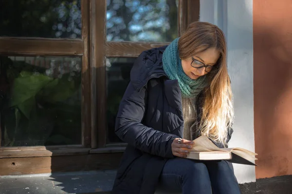 Kız cam kenarında oturan bir kitap okuyor — Stok fotoğraf