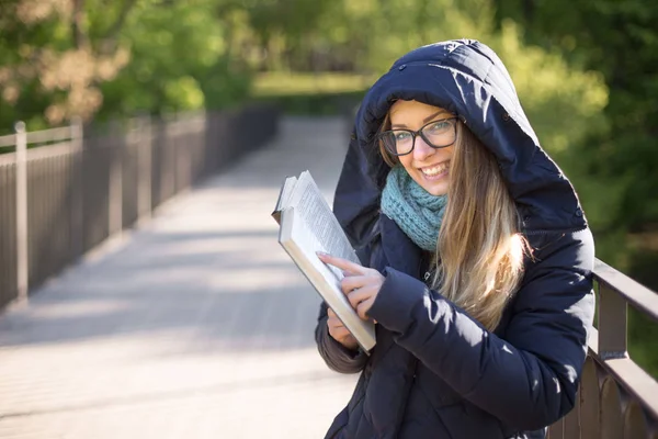 Menina feliz lendo um livro no corrimão . — Fotografia de Stock