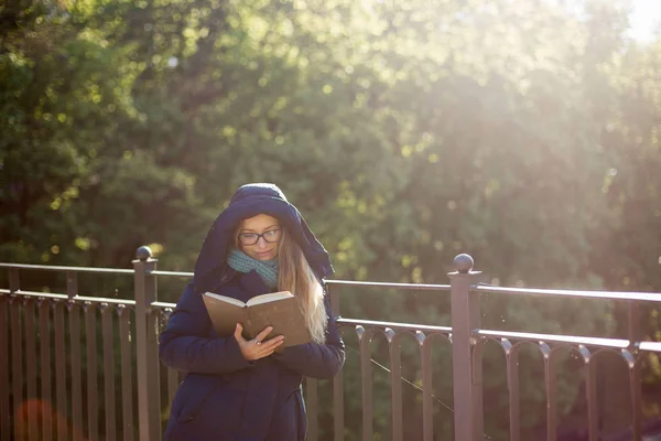 Glad tjej läser en bok på räcket. — Stockfoto