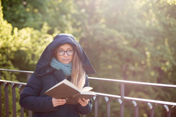 Ευτυχισμένος κορίτσι διαβάζοντας ένα βιβλίο στο κιγκλίδωμα. — Φωτογραφία Αρχείου