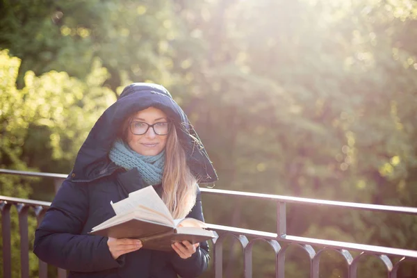 Glad tjej läser en bok på räcket. — Stockfoto