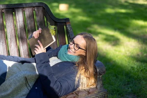 Flicka som läser en bok i parken på bänken — Stockfoto
