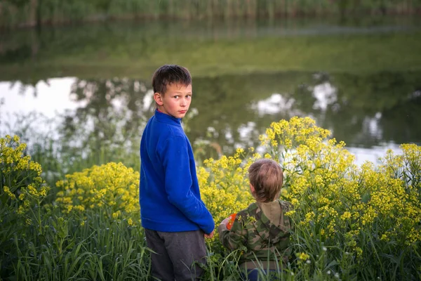 Dos chicos están de pie junto al agua . — Foto de Stock