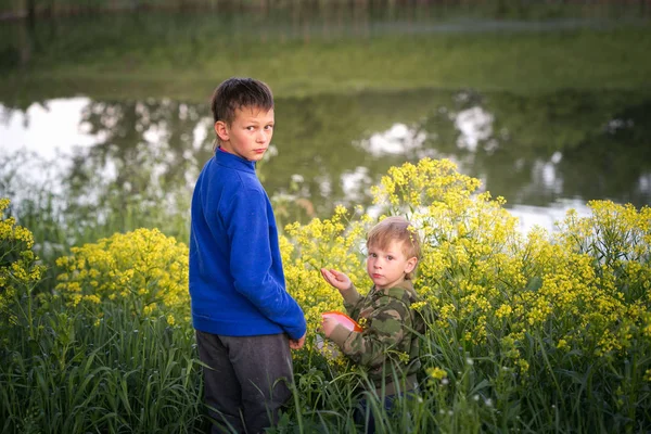 Dos chicos están de pie junto al agua . — Foto de Stock