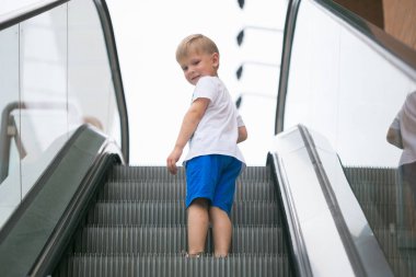 Little boy riding an escalator one dangerous. clipart