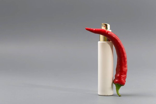 Hand with bottle of pepper spray isolated on gray background.