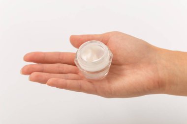 kadın elinde küçük cam kavanozda beyaz krema.