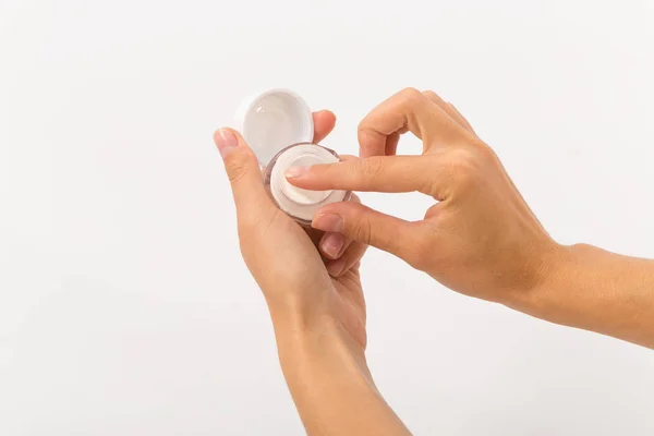 Crema blanca en un frasco de vidrio pequeño en manos femeninas . — Foto de Stock