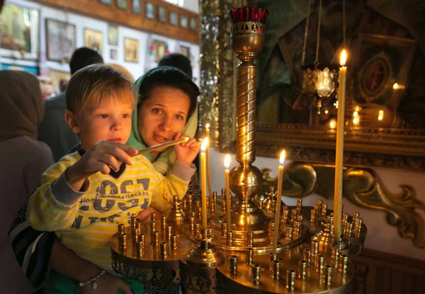 Ребенок с матерью, зажгущей свечу в церкви . — стоковое фото