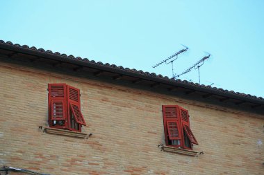 Windows bir tuğla duvara İtalya kırmızı panjurlar ile.