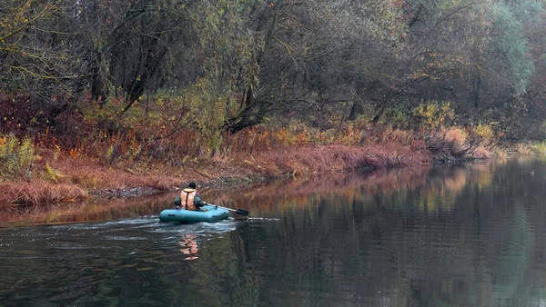 Pescador en un barco en el agua de un lago forestal en otoño . — Foto de Stock