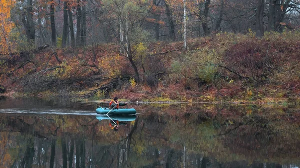 Fisherman in a boat on the water of a forest lake in autumn. — Stock Photo, Image