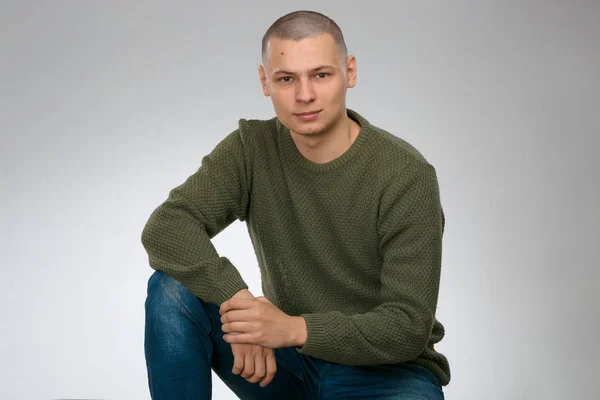 Een jongeman is skinhead in een groene militaire stijl trui. Studio. — Stockfoto